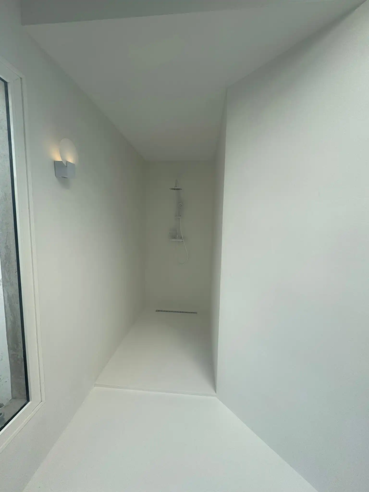 Ducha walk-in sin barreras con mampara de cristal templado y desagüe lineal en baño moderno