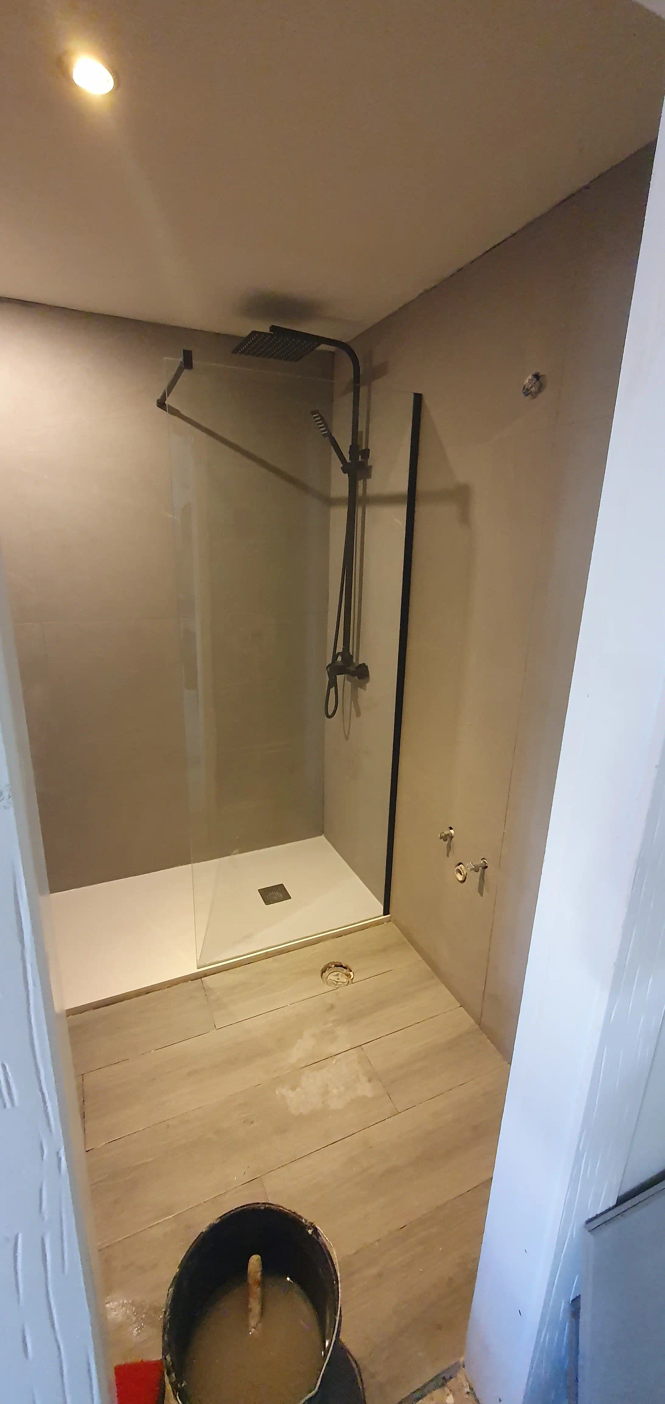 Ducha walk-in instalada con grifería ROCA efecto lluvia negro mate y mampara de cristal templado