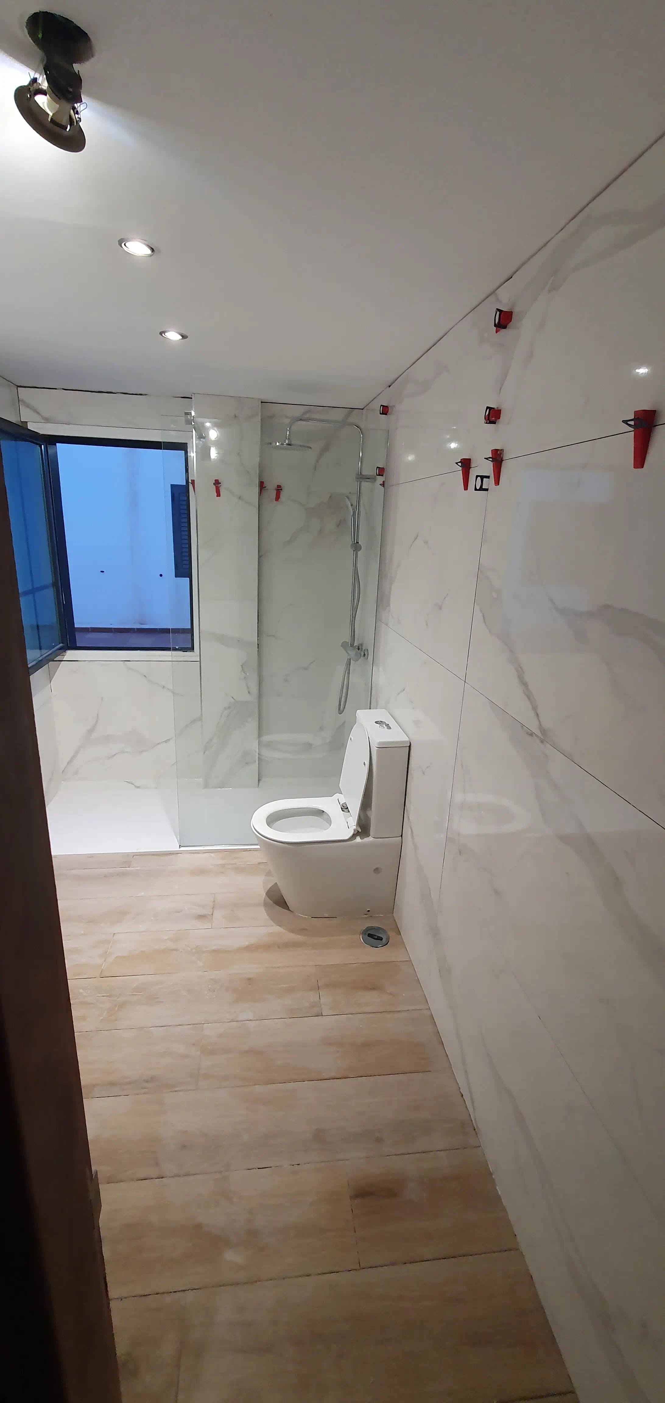 Perspectiva integral del baño renovado iluminado con focos Spot Light blancos