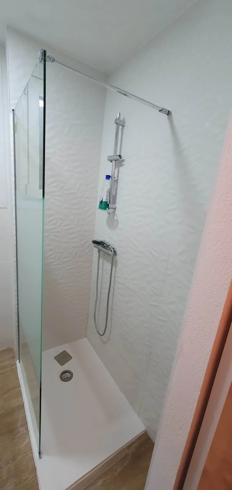 Zona de ducha finalizada con porcelanato 3D, plato ROCA y mampara templada