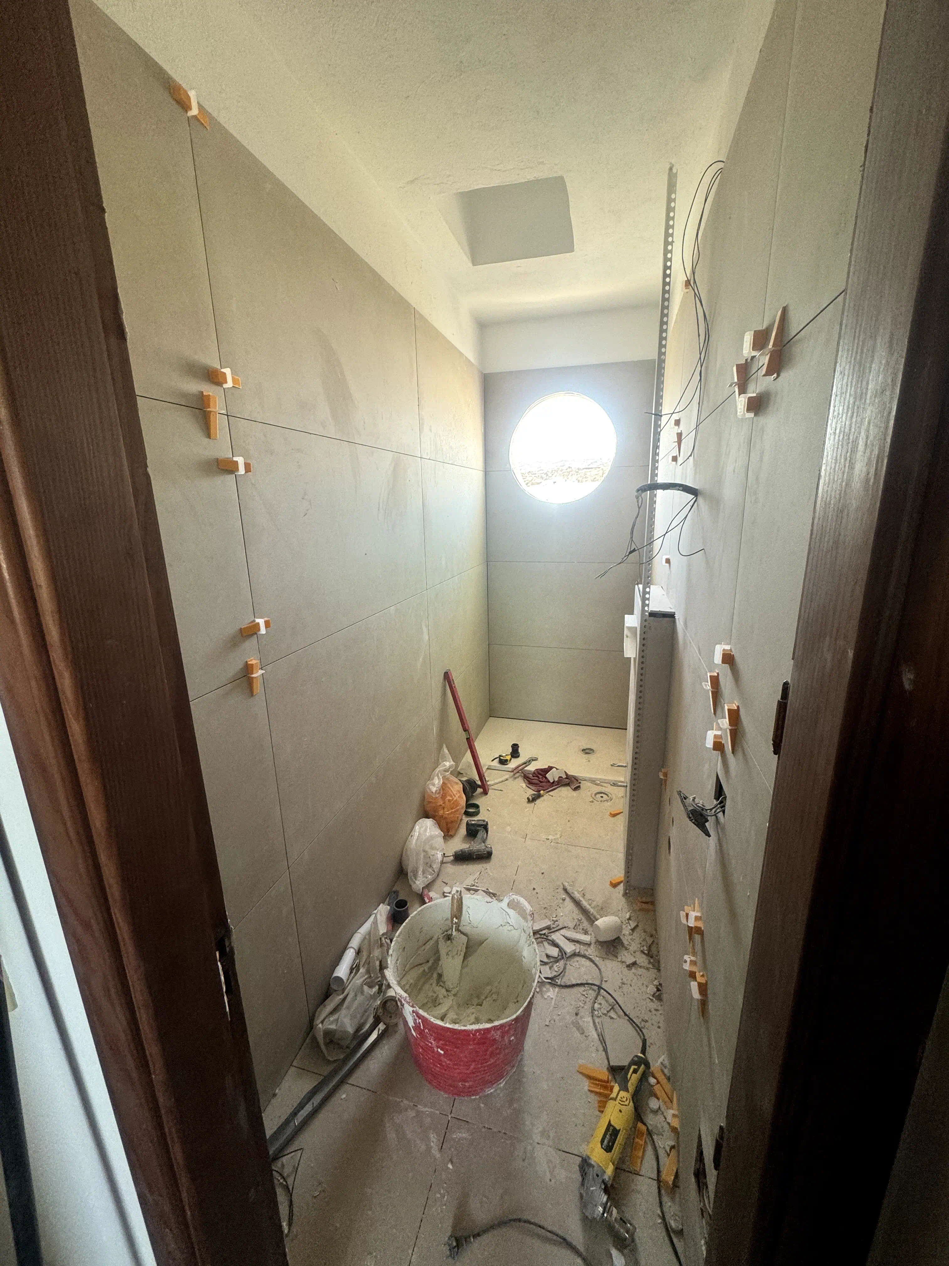 Proceso de instalación de porcelanato rectificado beige de gran formato 120x60 en paredes del baño