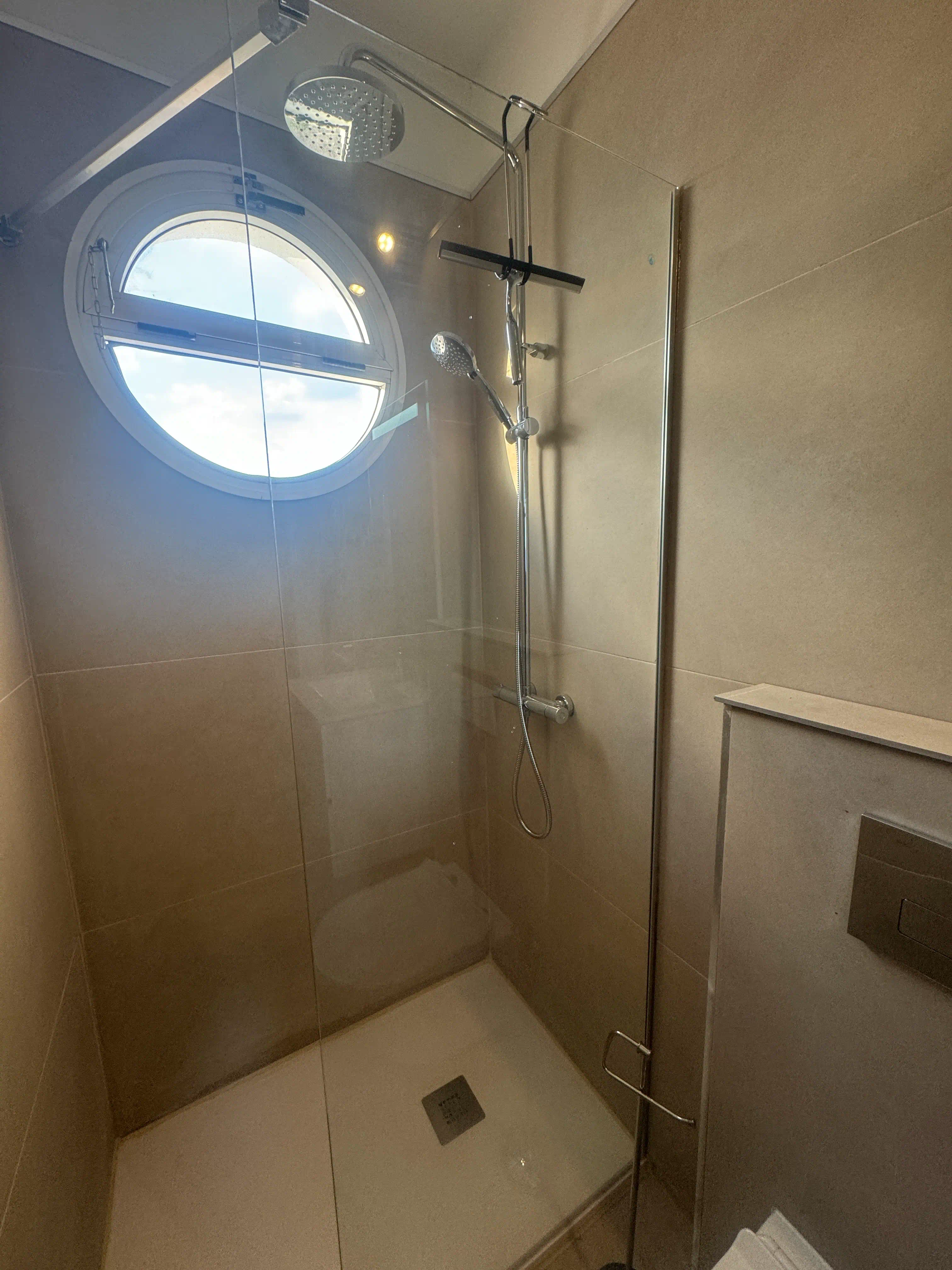 Zona de ducha walk-in con mampara fija de 80 cm, perfil cromado y columna efecto lluvia