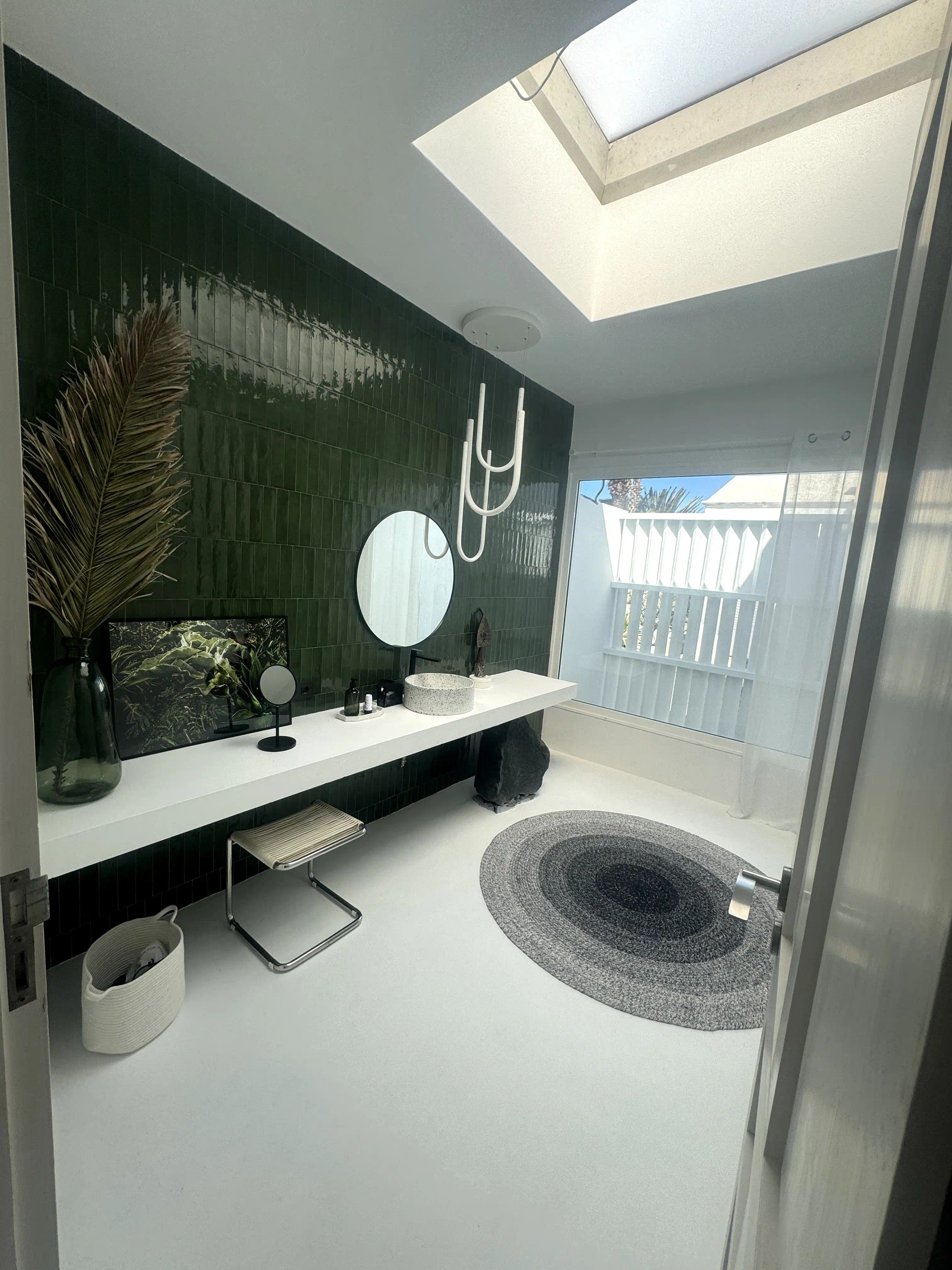 Zona de lavabo con encimera flotante, pared de porcelanato tipo metro verde y piedra volcánica