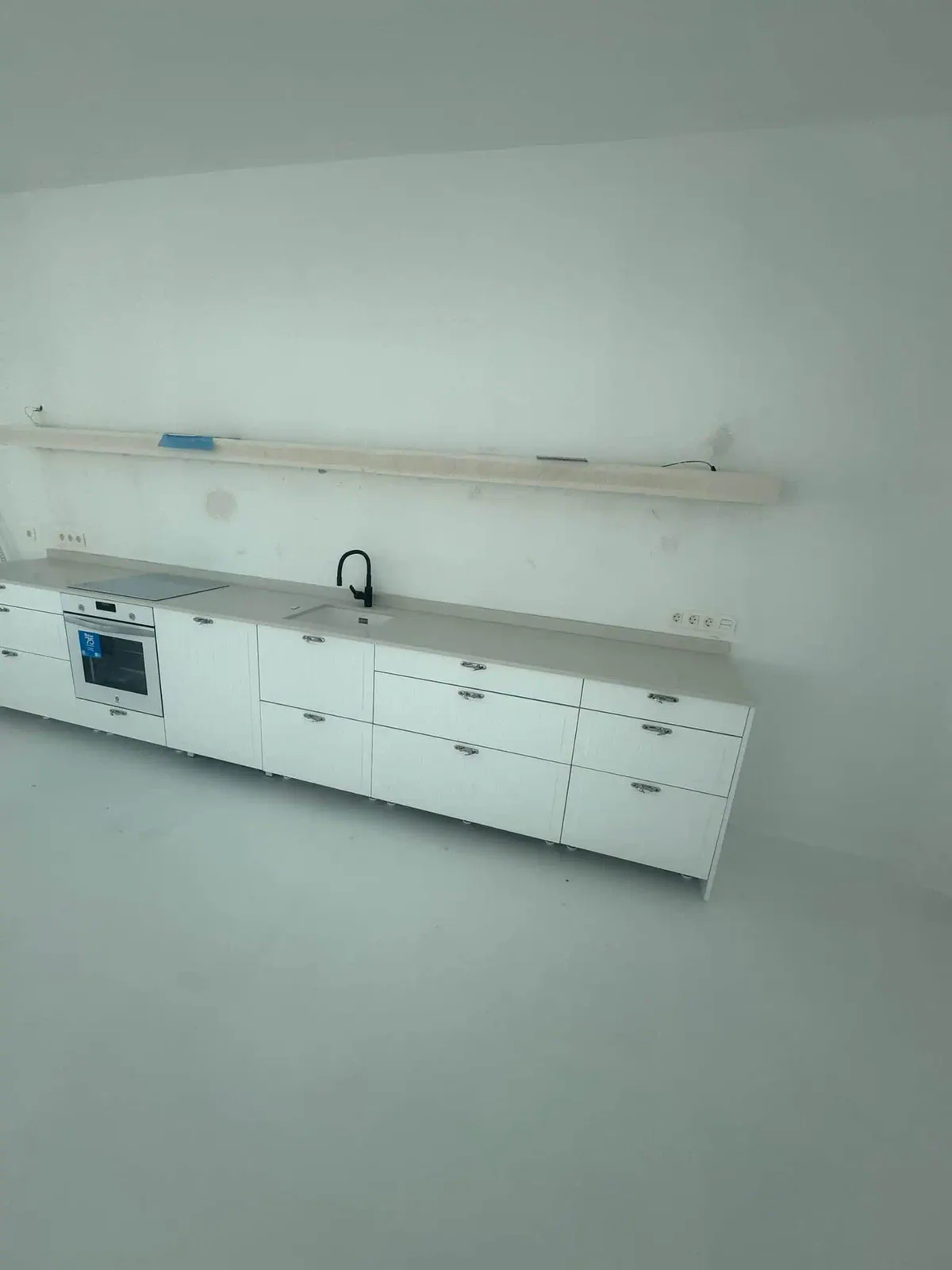 Detalle del montaje de la cocina lineal con la estantería flotante en ajuste