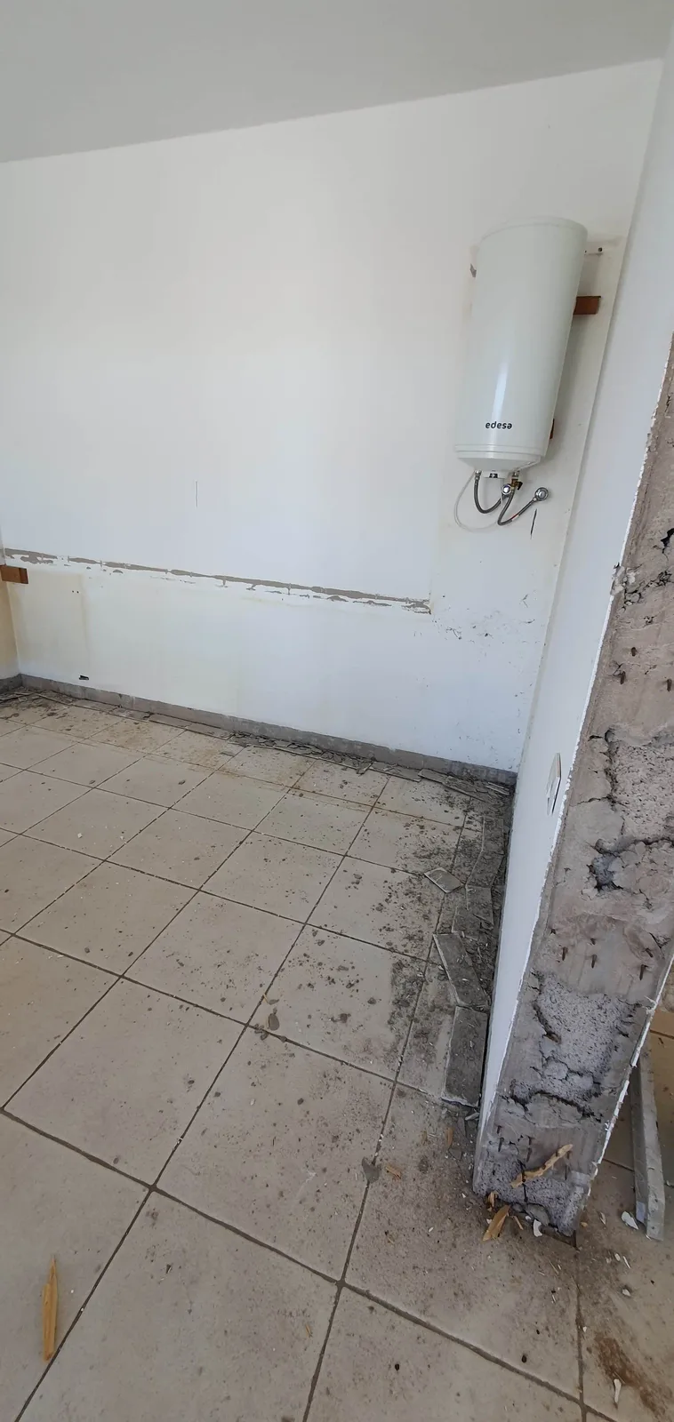 Cocina antigua completamente desmontada con el termo eléctrico a la vista