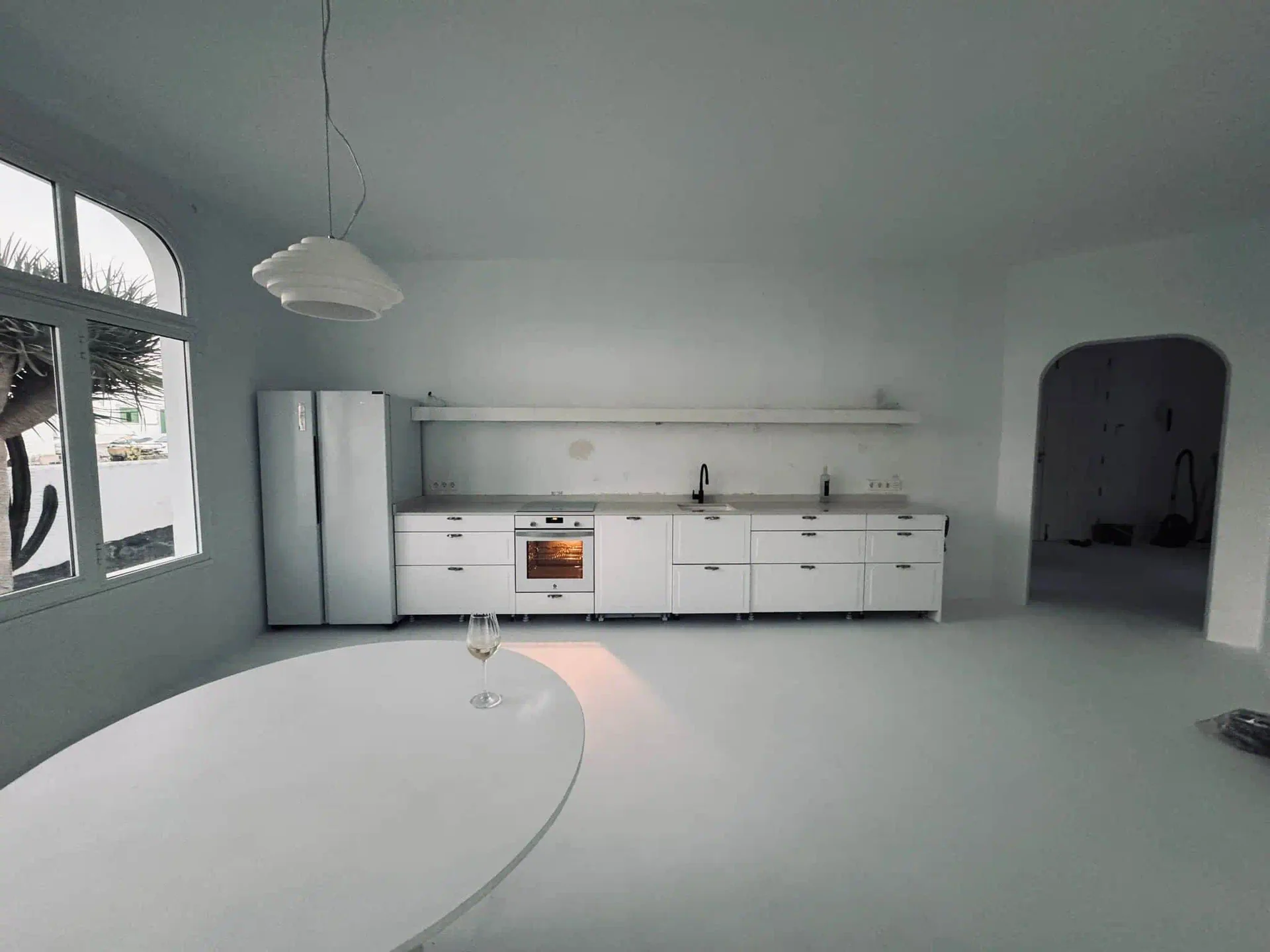 Zona día unificada con suelo epóxico blanco continuo, comedor y cocina abierta en quinta de Guataparo